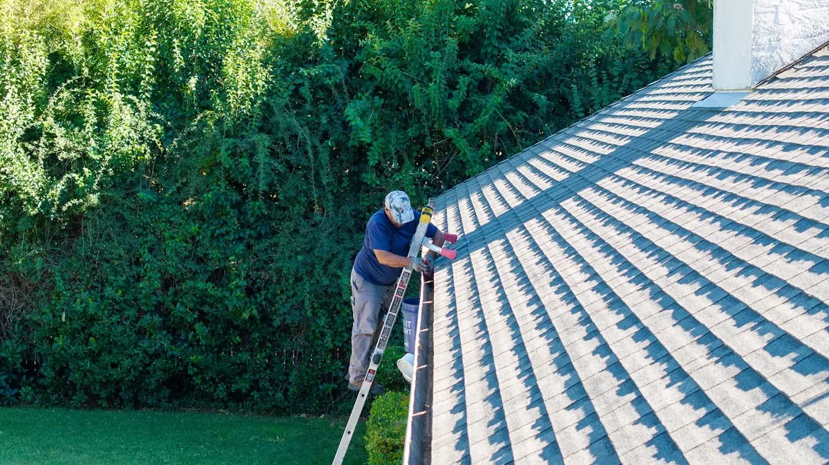 Shasta Gutter Cleaning and Guards technician hand-clearing a clogged gutter in Redding