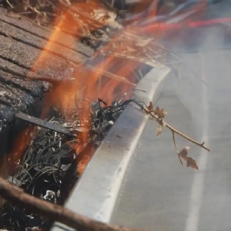 A clogged gutter full of dry leaves and pine needles catching fire