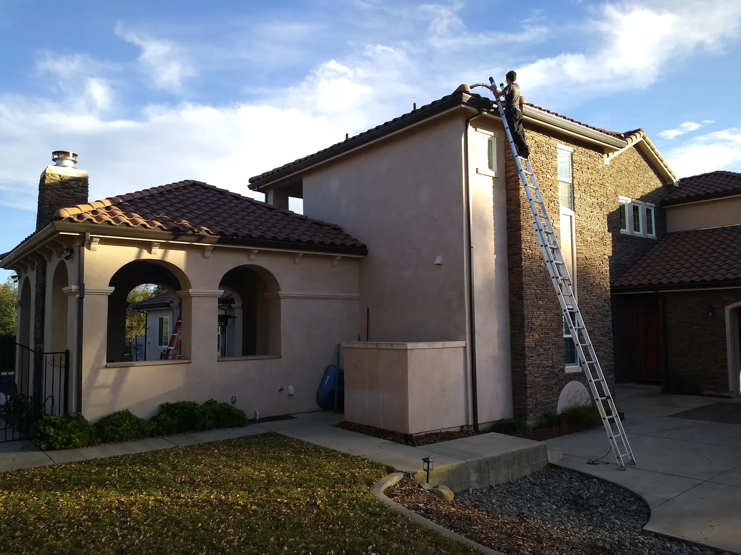 Shasta Gutter Cleaning and Guards crew on a ladder cleaning the gutters of a Redding-area home
